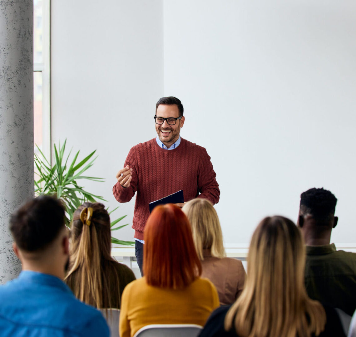 Corporate speaker delivering a motivating training session to a group of diverse employees.