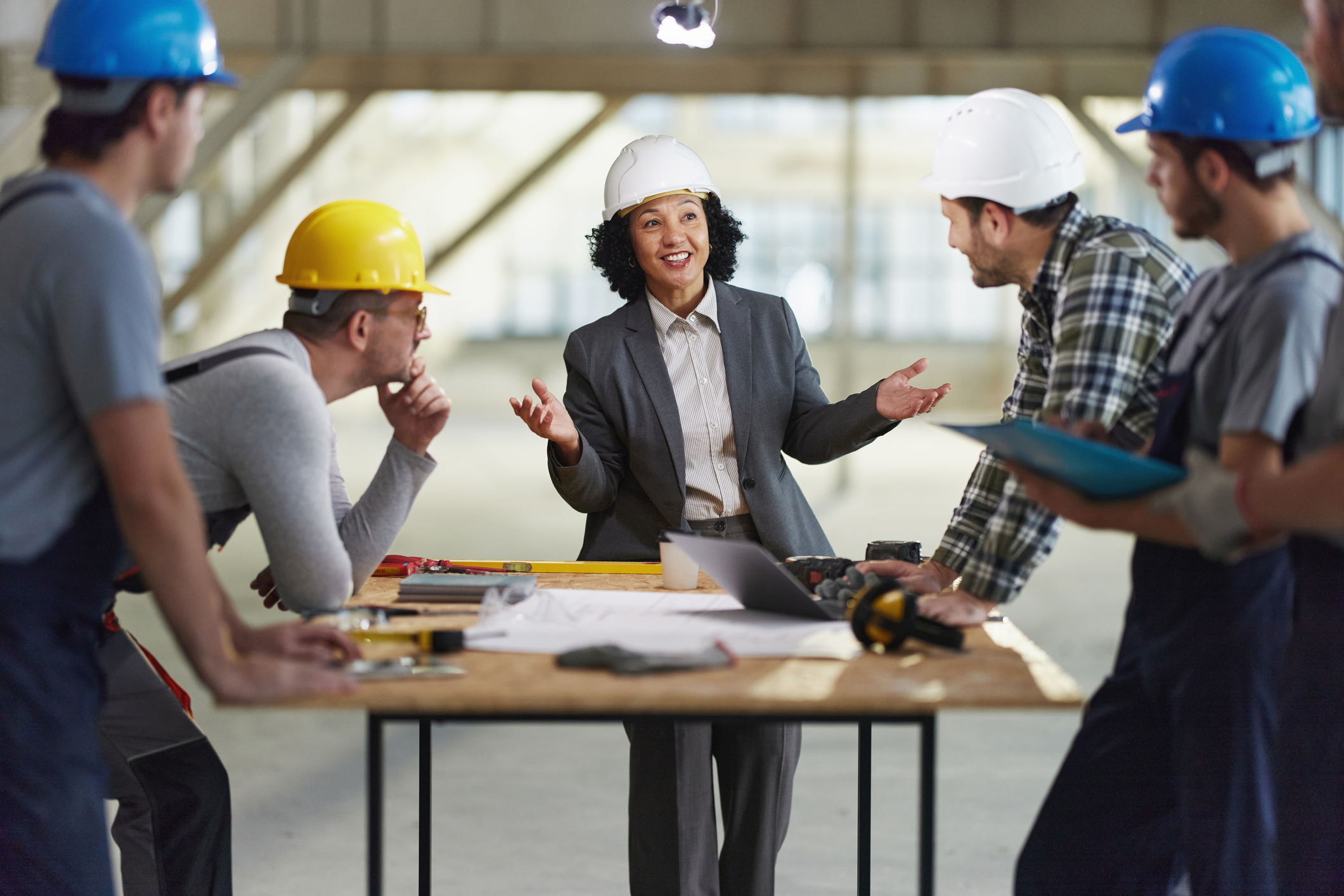 Team of manual workers having a meeting with their real estate developer at construction site.